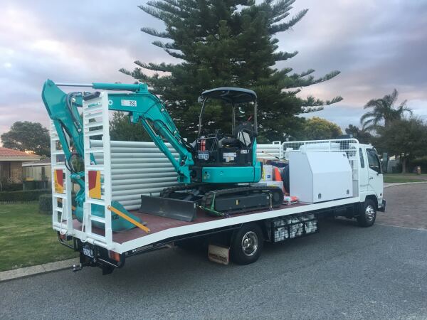 Work truck carrying a compact excavator